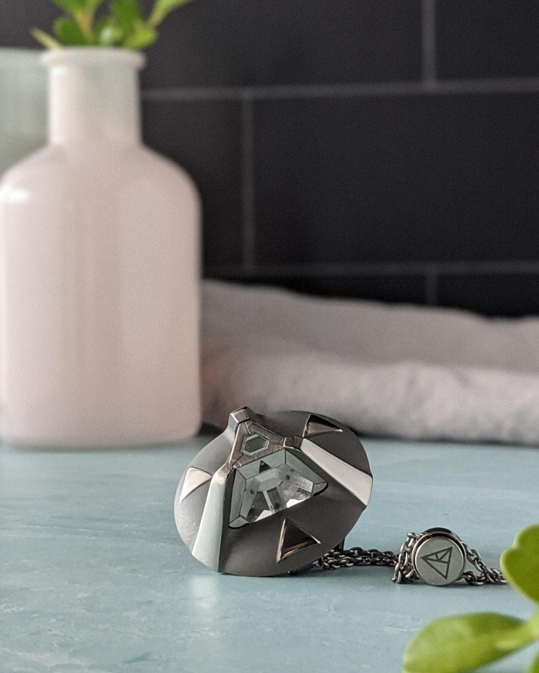 The ARK Pendant necklace with a white vase in the background